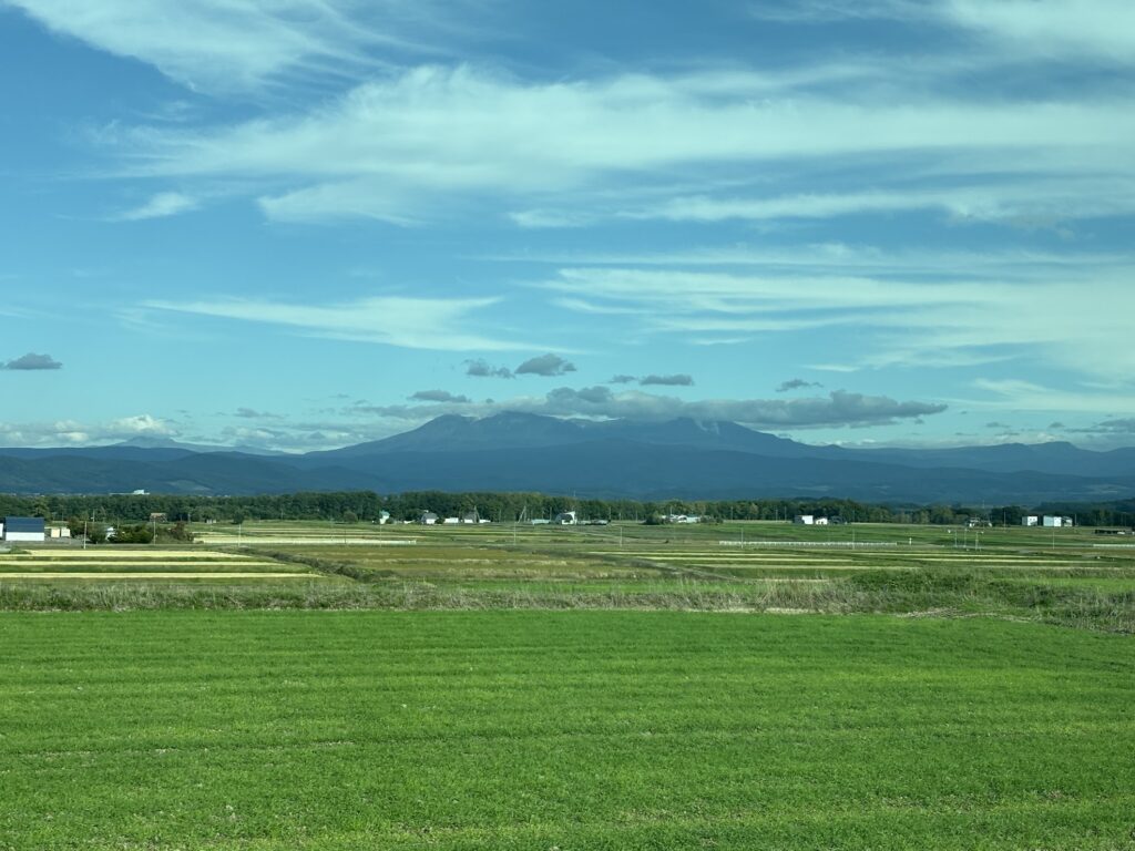 ノースライナーの車窓から見える山並みと畑